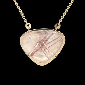 a gold necklace with a pink and white pendant