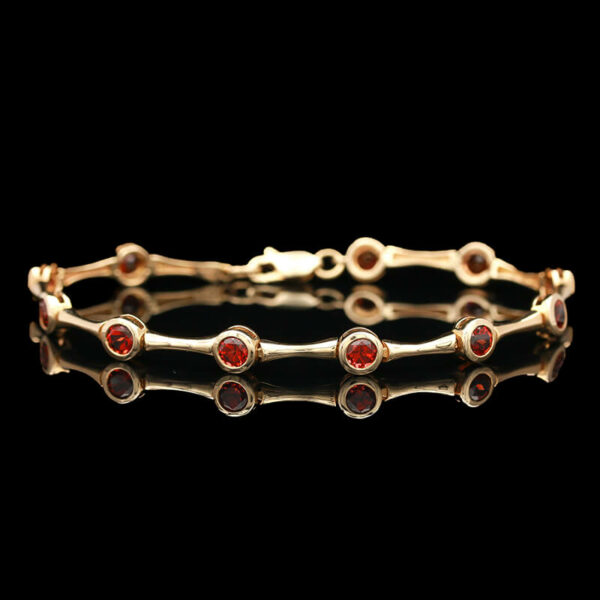 a gold bracelet with red stones on it