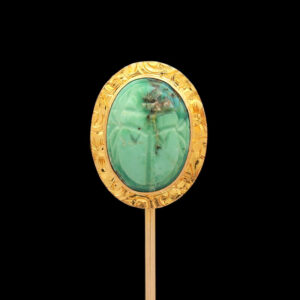 a gold and green broochele on a stick