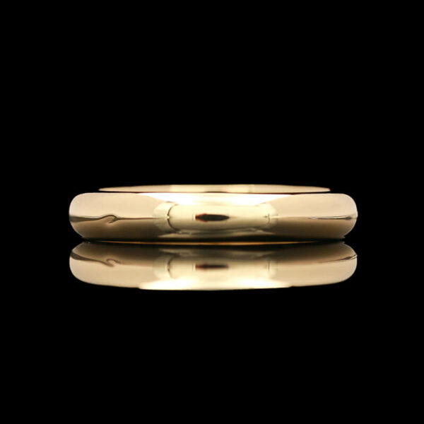 a gold wedding band on a black background