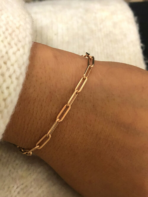 a person wearing a gold chain bracelet on their arm