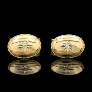 two gold cufflinks with diamonds on them
