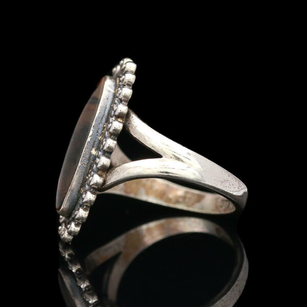 a silver ring with beads and stones on it