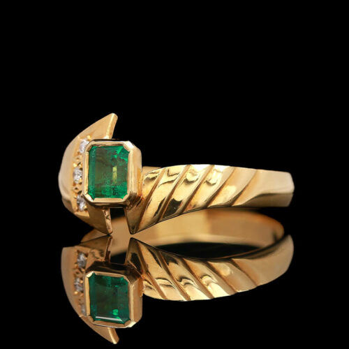 a gold ring with two emeralds and diamonds