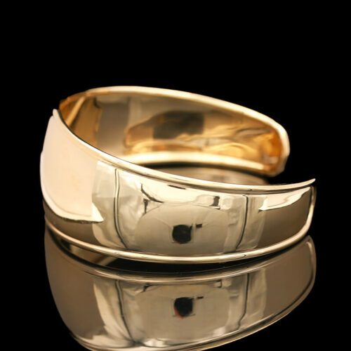 two gold and silver bracelets on a reflective surface