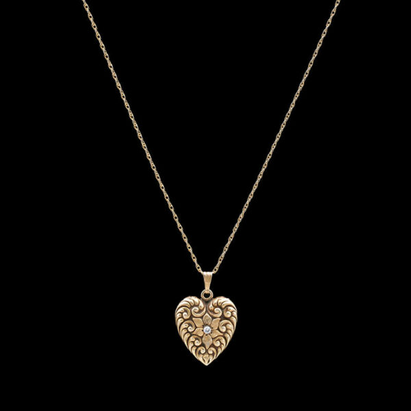 a gold heart pendant with diamonds on a black background