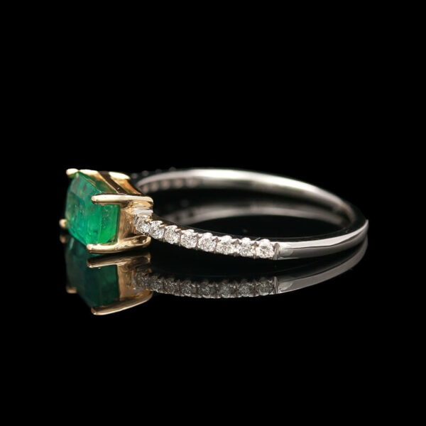 an emerald and diamond ring on a black background