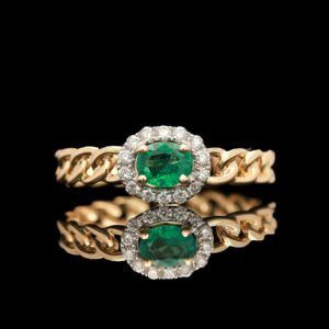 an emerald and diamond ring on a black background