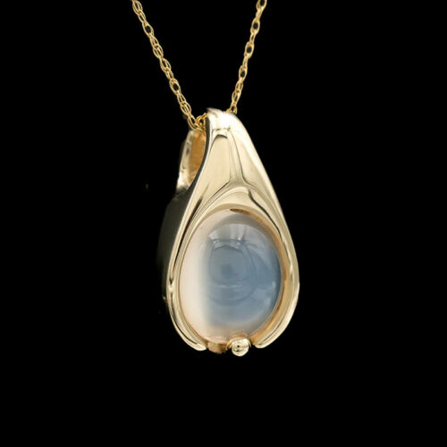 a gold pendant with a white stone in the center