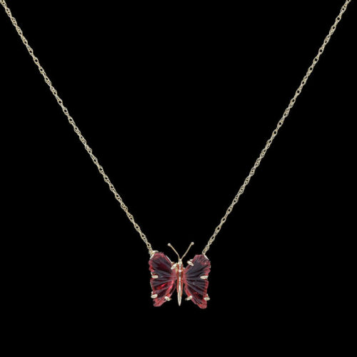 a red butterfly necklace on a gold chain