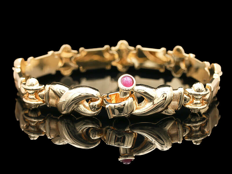 a gold bracelet with a pink stone in the center