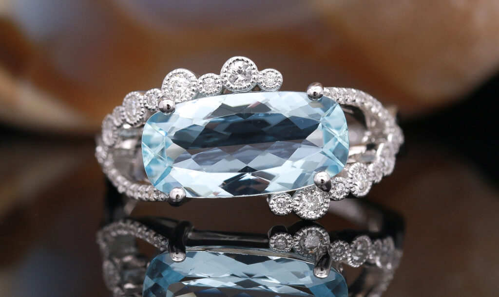 Professional photo of the final ring, featuring a large aquamarine stone surrounded by small diamonds.