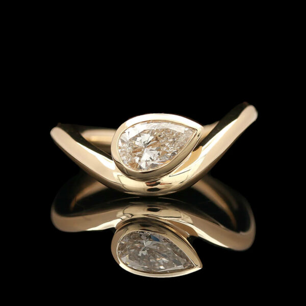 a yellow gold ring with two pear shaped diamonds
