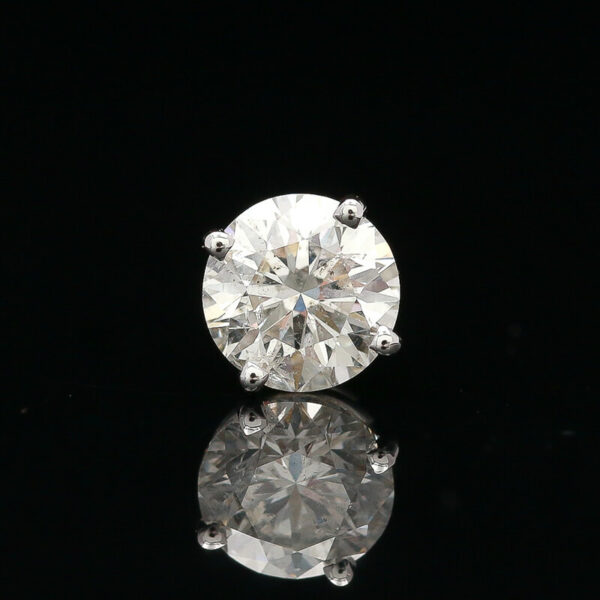a round brilliant cut diamond sits on a reflective surface