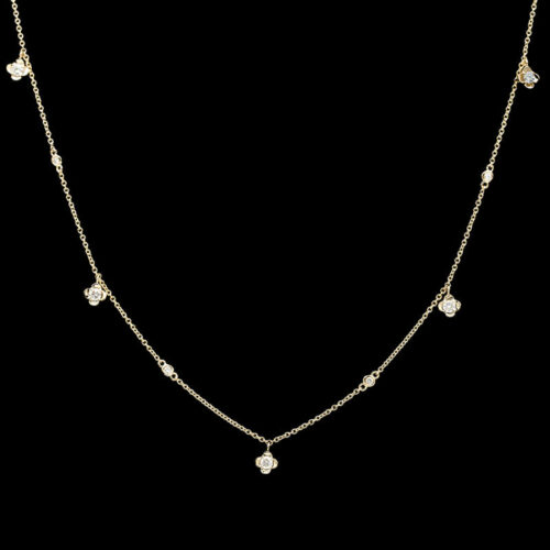 a gold necklace with white stones on a black background