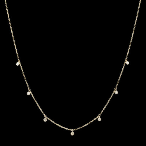 a gold necklace with white pearls on a black background