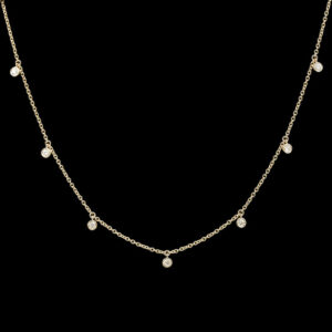 a gold necklace with pearls on a black background
