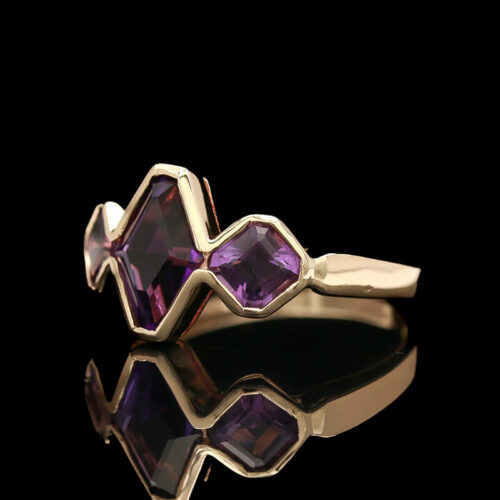 a gold ring with two purple stones on it