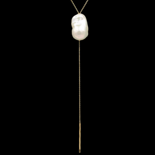 a long gold chain with a white glass ball hanging from it