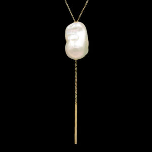 a long gold chain with a white pearl on it