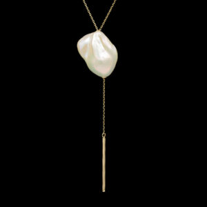 a long necklace with a large white pearl hanging from it