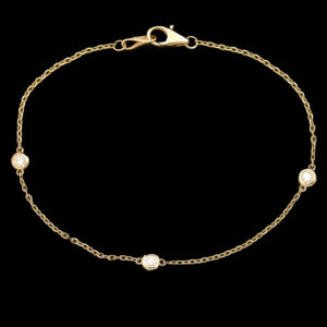 a gold chain bracelet with three white stones
