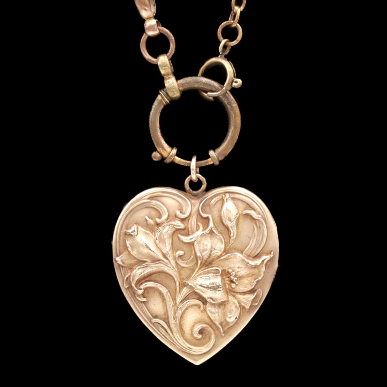 A gold heart-shaped locket featuring an intricate floral motif
