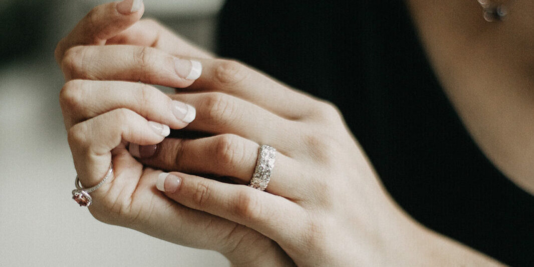 Close up shot of well manicured hands wearing gold rings